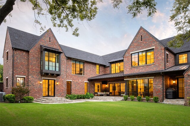 back of property with metal roof, a standing seam roof, and brick siding