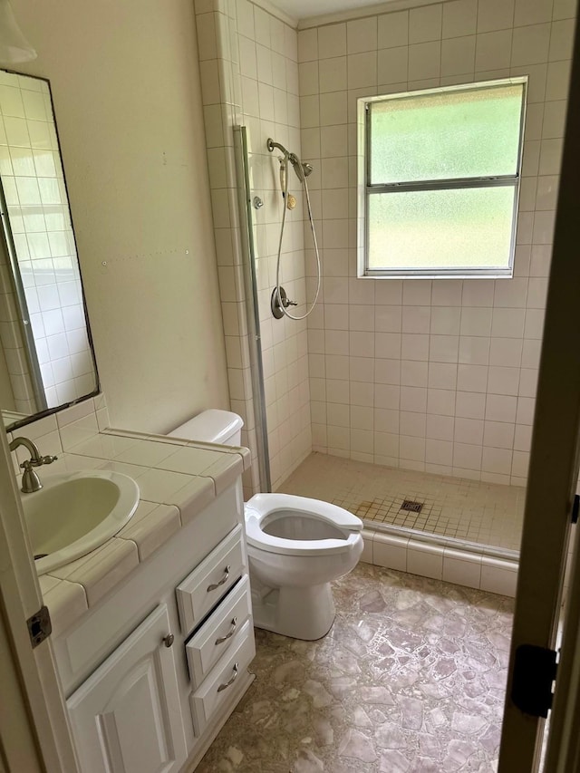 bathroom featuring vanity, tiled shower, and toilet