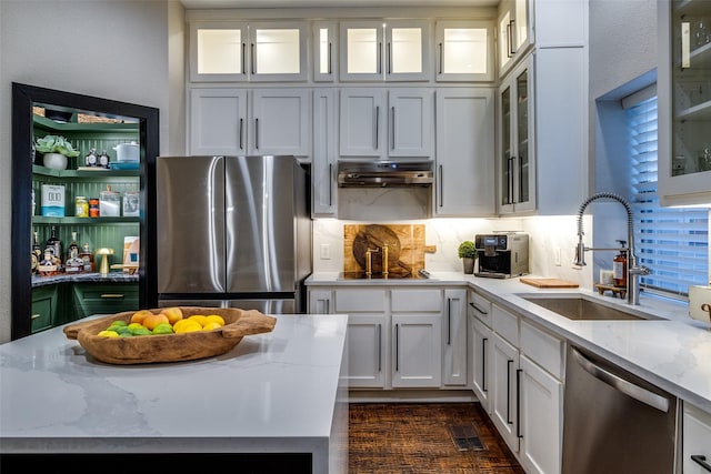 kitchen featuring light stone countertops, appliances with stainless steel finishes, backsplash, sink, and white cabinetry