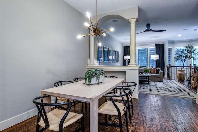 dining room with wood-type flooring, ceiling fan with notable chandelier, decorative columns, and ornamental molding