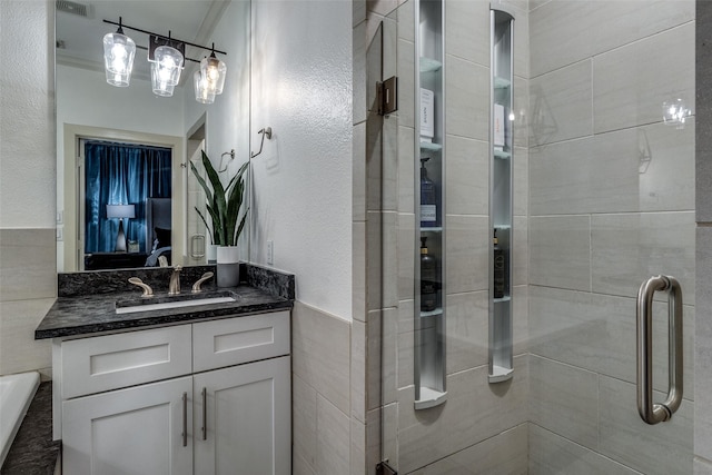 bathroom with vanity, an enclosed shower, and tile walls