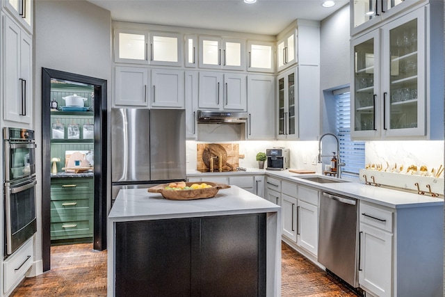 kitchen featuring sink, stainless steel appliances, a kitchen island, tasteful backsplash, and white cabinets