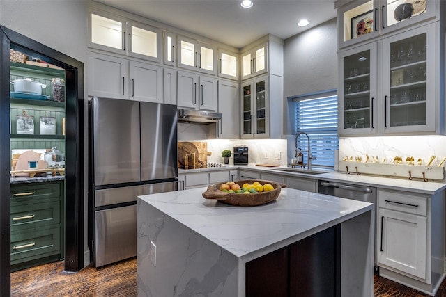 kitchen with light stone countertops, white cabinetry, sink, a center island, and stainless steel appliances