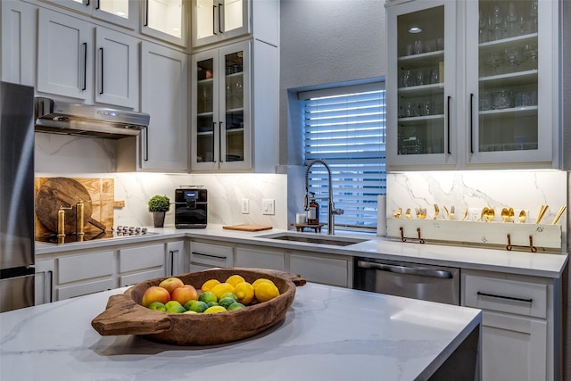 kitchen featuring backsplash, light stone counters, sink, and stainless steel appliances