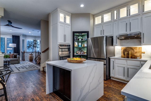 kitchen with light stone counters, a kitchen island, white cabinets, and appliances with stainless steel finishes