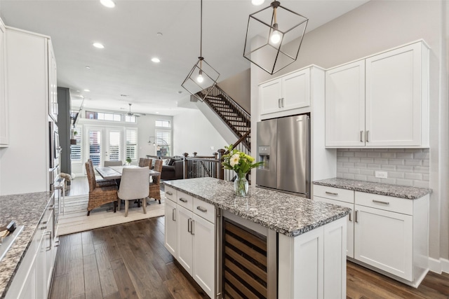 kitchen featuring white cabinets, stainless steel fridge with ice dispenser, beverage cooler, and pendant lighting