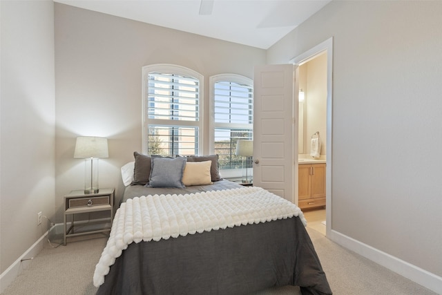 bedroom with ensuite bath, light carpet, and ceiling fan