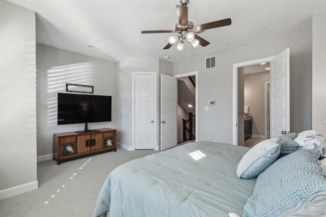 carpeted bedroom with ensuite bathroom and ceiling fan