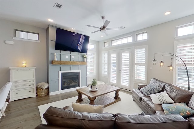 living room with plenty of natural light, a large fireplace, dark hardwood / wood-style flooring, and ceiling fan