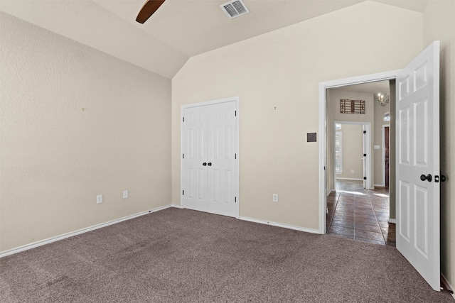 unfurnished bedroom featuring ceiling fan, a closet, vaulted ceiling, and dark colored carpet