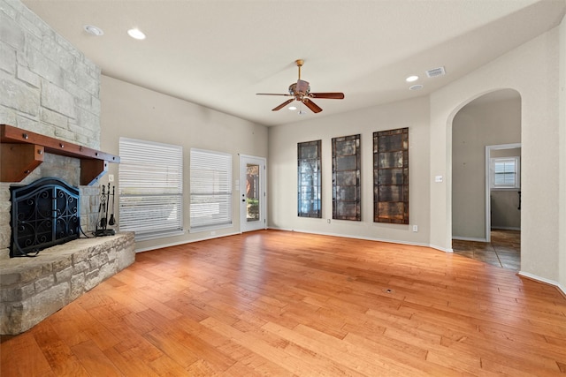 unfurnished living room featuring ceiling fan, light wood-type flooring, and a fireplace