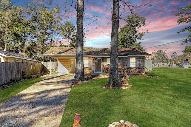 ranch-style home featuring a carport and a yard