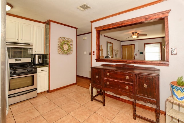 kitchen with ceiling fan, stainless steel gas range, tasteful backsplash, white cabinets, and ornamental molding