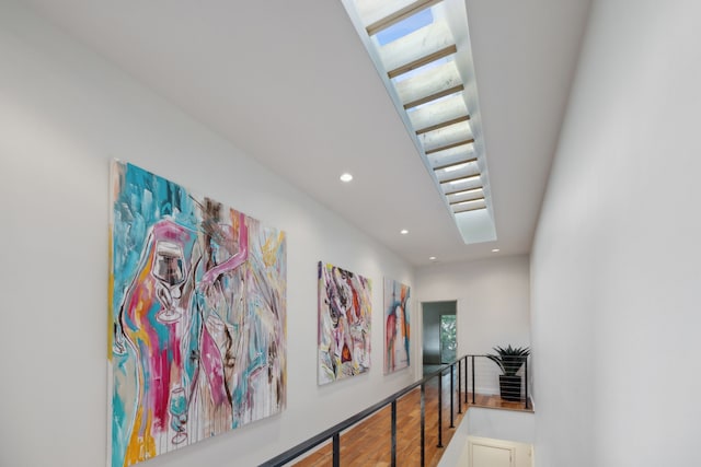 hall featuring a skylight, a wealth of natural light, and hardwood / wood-style flooring