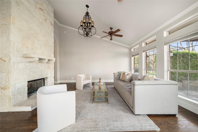 living room featuring ceiling fan with notable chandelier, dark hardwood / wood-style floors, a stone fireplace, and ornamental molding