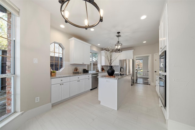 kitchen featuring white cabinetry, stainless steel appliances, backsplash, decorative light fixtures, and a kitchen island