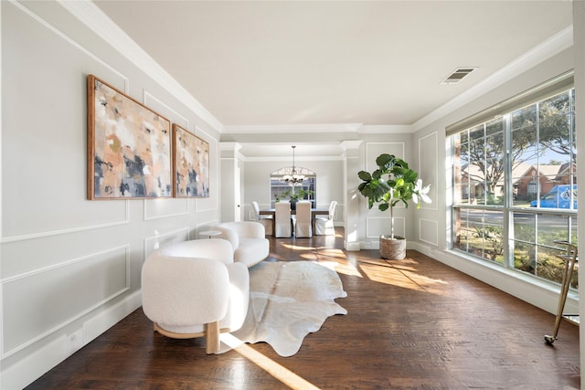 living area featuring a chandelier, wood-type flooring, plenty of natural light, and crown molding