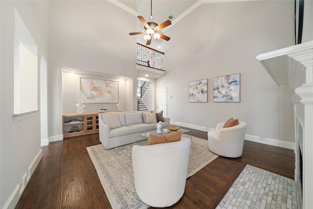 living room with ceiling fan, a towering ceiling, and dark hardwood / wood-style floors