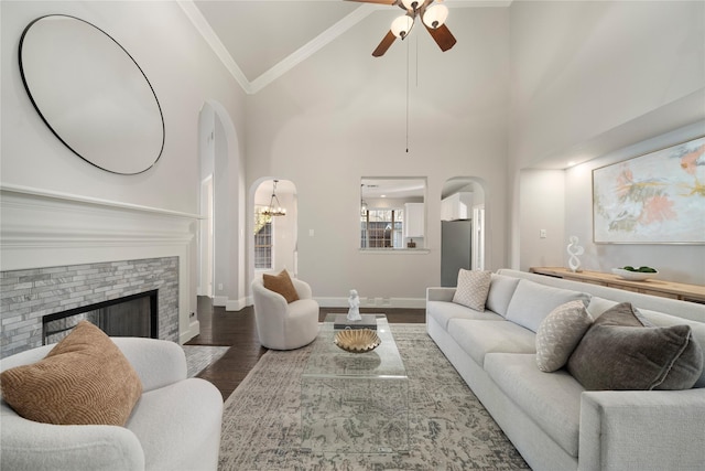 living room with crown molding, high vaulted ceiling, dark wood-type flooring, and ceiling fan with notable chandelier