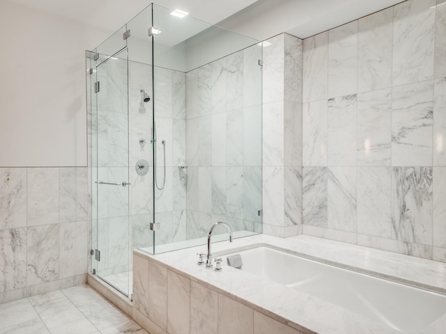 bathroom with tile walls and shower with separate bathtub