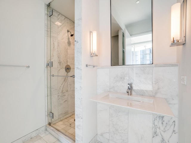 bathroom with a shower with shower door and sink