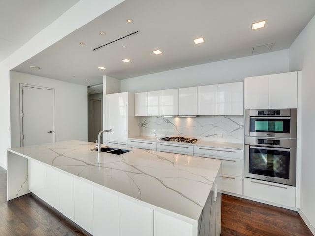 kitchen featuring sink, white cabinets, and a center island with sink