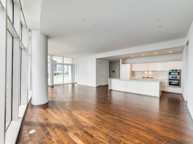 unfurnished living room with floor to ceiling windows and dark hardwood / wood-style flooring