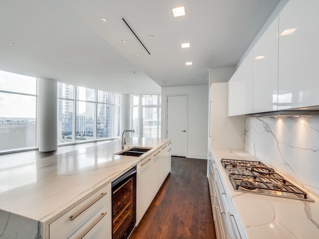 kitchen featuring decorative backsplash, light stone counters, sink, and beverage cooler