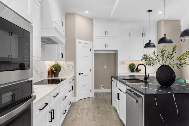 kitchen featuring dark stone counters, stainless steel appliances, sink, white cabinets, and hanging light fixtures