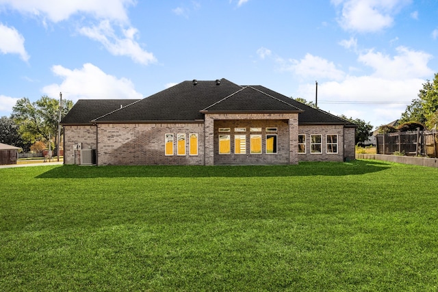 rear view of house with central AC and a lawn