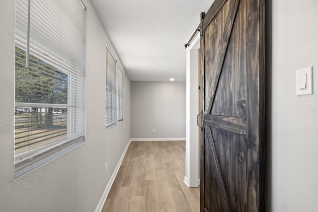 hall with a barn door and light hardwood / wood-style flooring