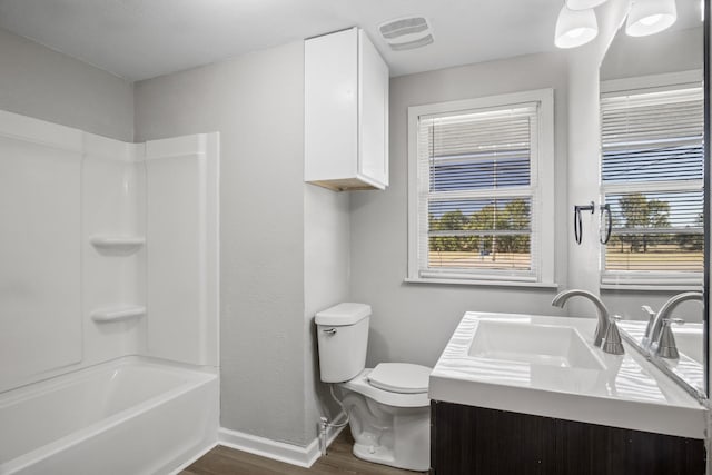 full bathroom featuring washtub / shower combination, vanity, hardwood / wood-style flooring, and toilet