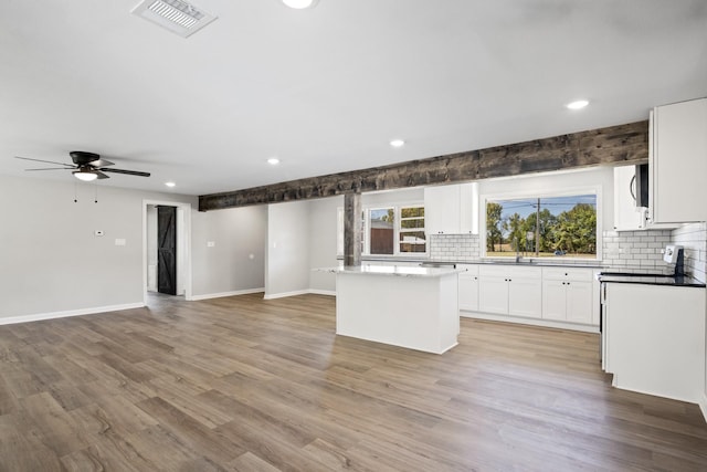 kitchen with ceiling fan, a center island, light hardwood / wood-style floors, white cabinetry, and range with electric stovetop