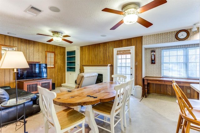 dining area featuring wooden walls, a fireplace, and a healthy amount of sunlight