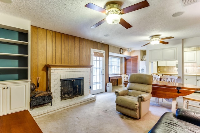 carpeted living room with a fireplace, wooden walls, a textured ceiling, and ceiling fan