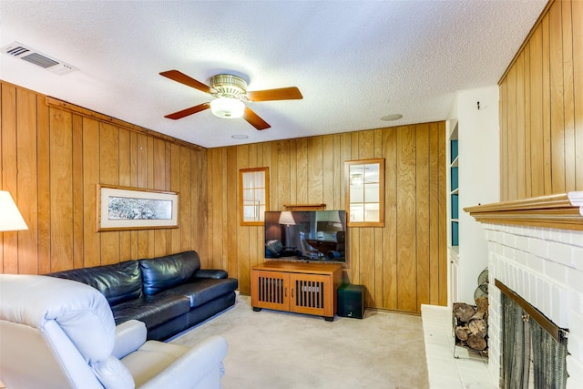 carpeted living room with a textured ceiling, a brick fireplace, and ceiling fan