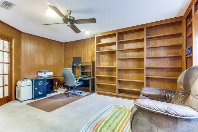 office space with ornamental molding, light colored carpet, ceiling fan, and wood walls