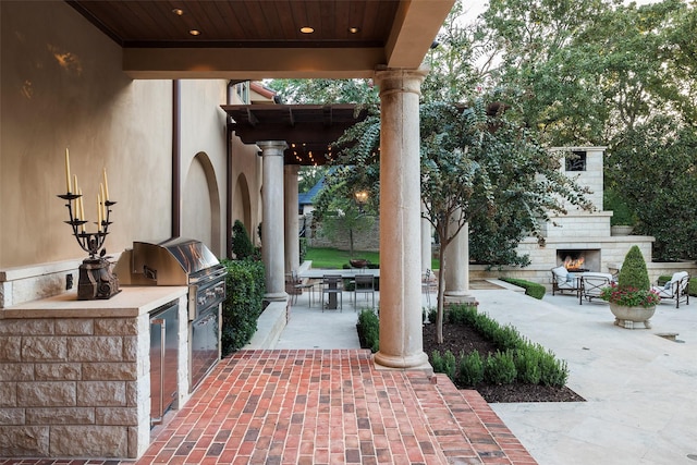 view of patio featuring an outdoor fireplace, exterior kitchen, and a grill