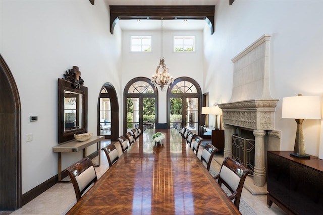 dining space featuring french doors, a chandelier, a high ceiling, and a tile fireplace