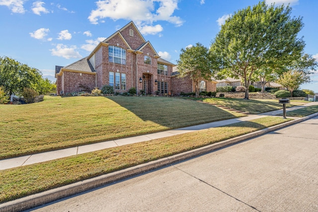 view of front facade featuring brick siding and a front yard