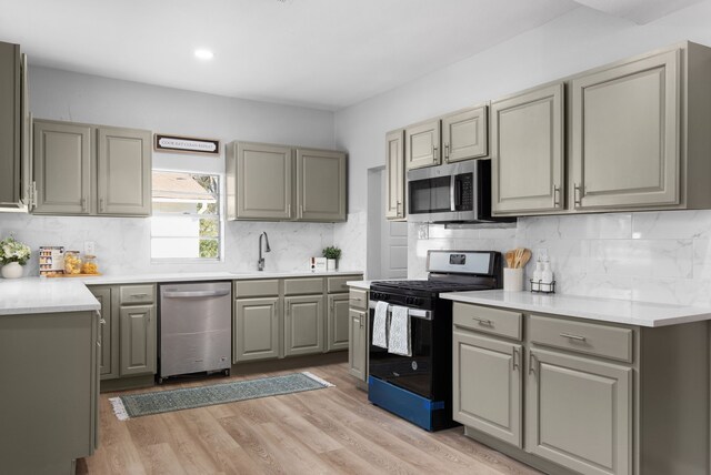 kitchen with decorative backsplash, appliances with stainless steel finishes, light hardwood / wood-style floors, and gray cabinetry