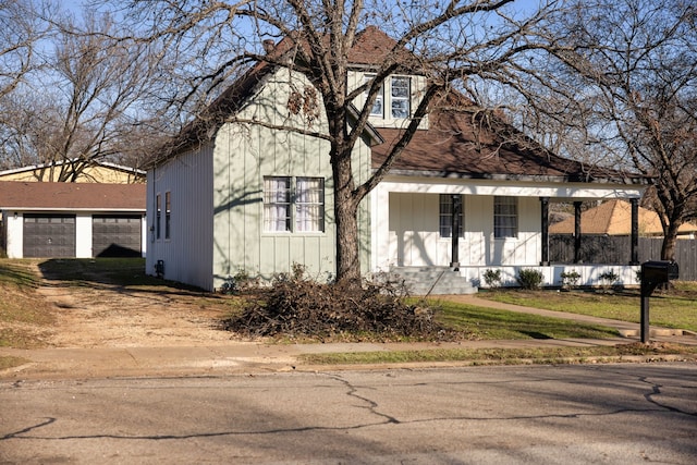 view of front of home featuring a garage, covered porch, and an outbuilding