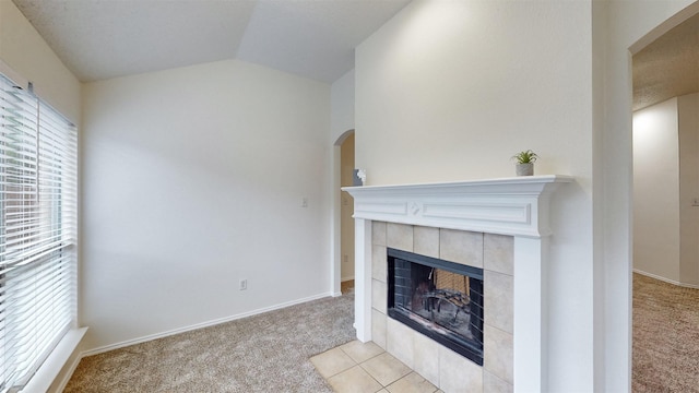 unfurnished living room featuring light colored carpet, vaulted ceiling, and a tiled fireplace