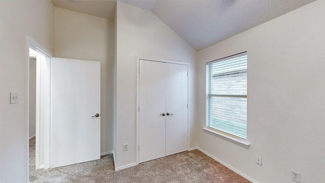 unfurnished bedroom featuring light carpet, vaulted ceiling, and a closet