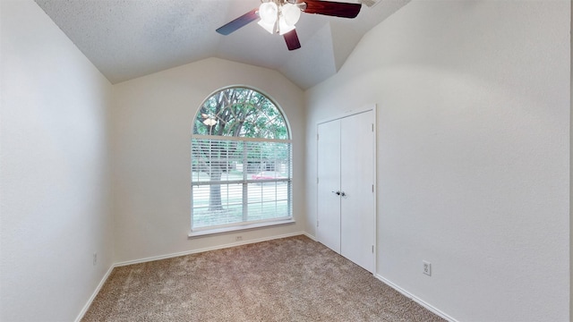 spare room with ceiling fan, a healthy amount of sunlight, carpet floors, and vaulted ceiling