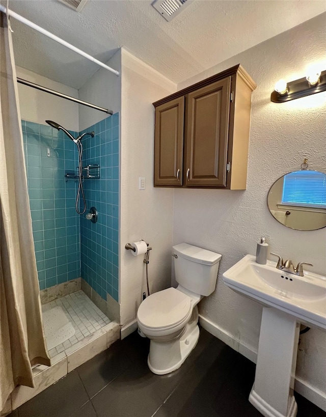 bathroom featuring tile patterned floors, toilet, a textured ceiling, and a shower with shower curtain