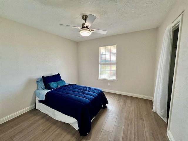 bedroom with ceiling fan, hardwood / wood-style floors, and a textured ceiling