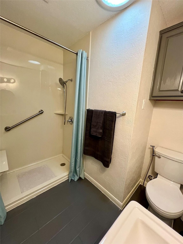 bathroom with a textured ceiling, toilet, and walk in shower