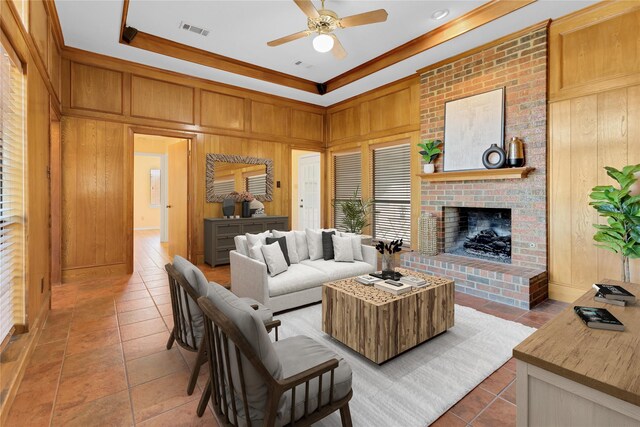 tiled living room featuring wood walls, a fireplace, ceiling fan, and crown molding