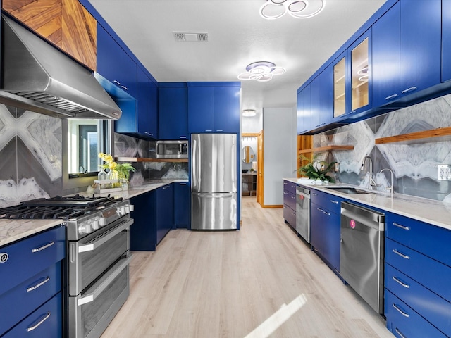 kitchen with blue cabinets, sink, stainless steel appliances, range hood, and light hardwood / wood-style floors